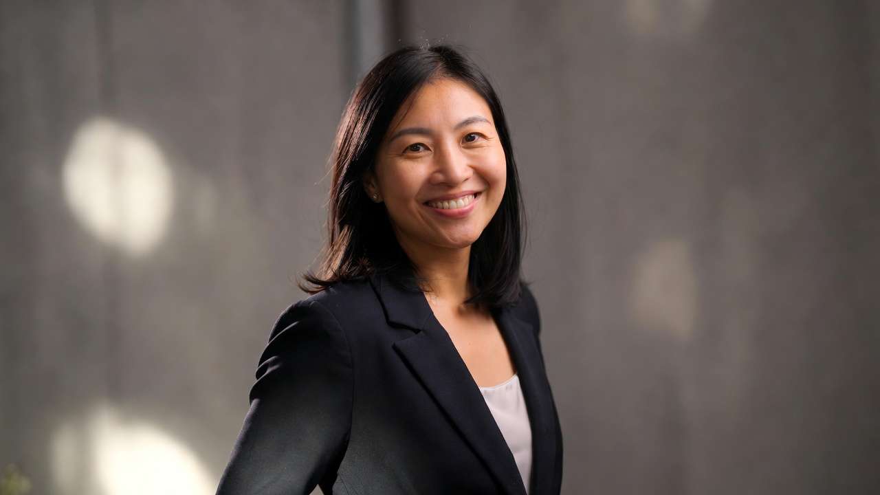 East Asian woman headshot, business attire, smile